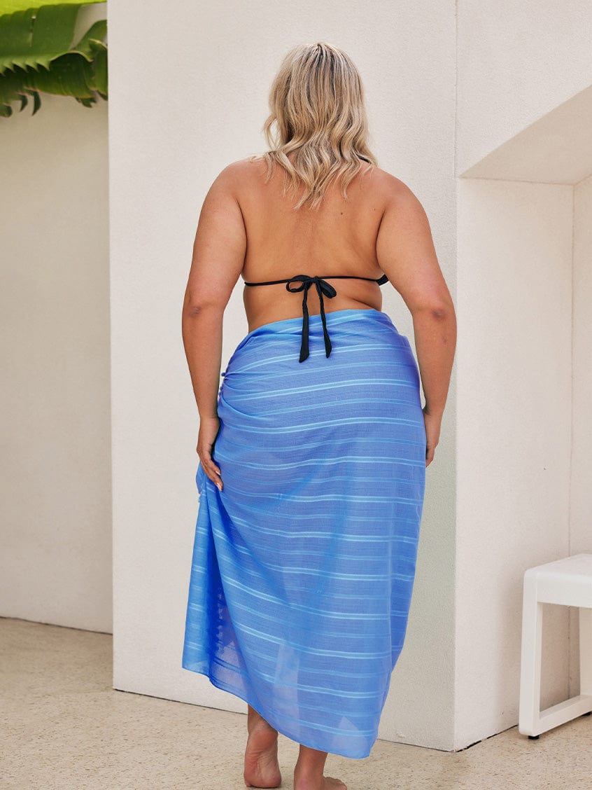 Back of model wearing a long blue sarong with pom pom detail