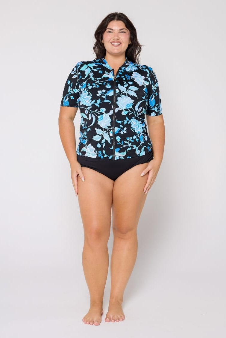 Woman wearing a black floral shirt and black swimsuit on a white background