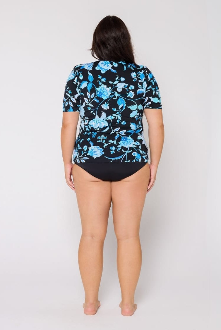 Woman wearing a black swimsuit with blue floral patterns on a white background
