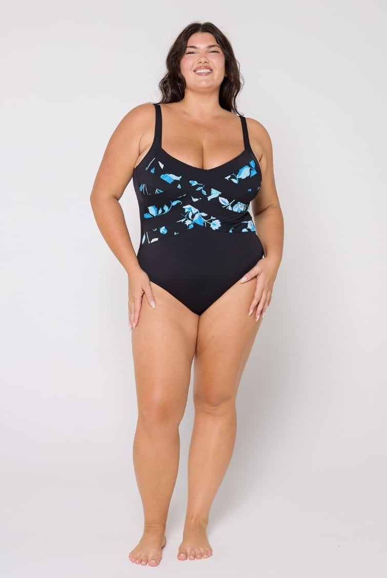 Woman wearing a black one-piece swimsuit with blue fish pattern on a white background