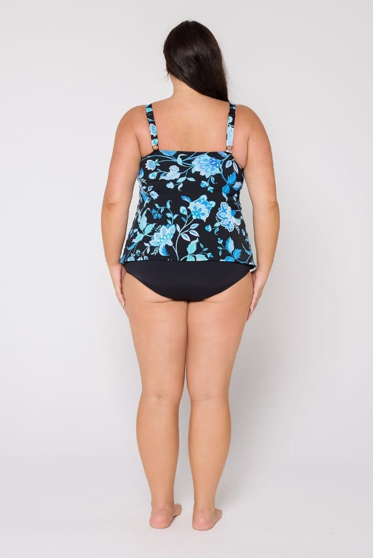 Woman wearing a floral black and blue swimsuit top on a white background