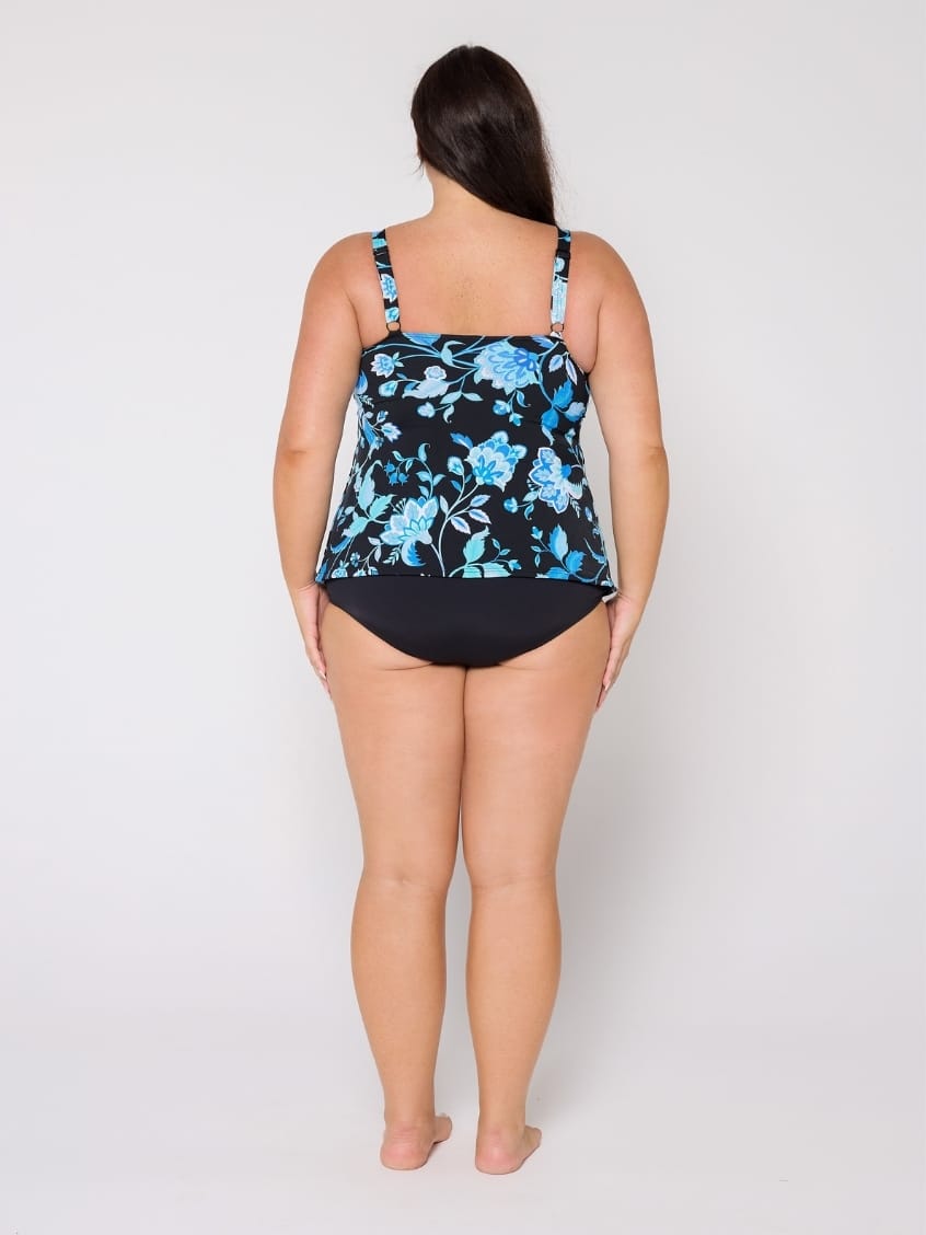 Woman wearing a floral black and blue swimsuit top on a white background