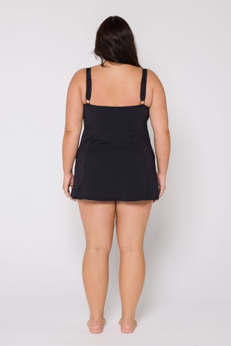 Woman wearing a black slip dress against a white background