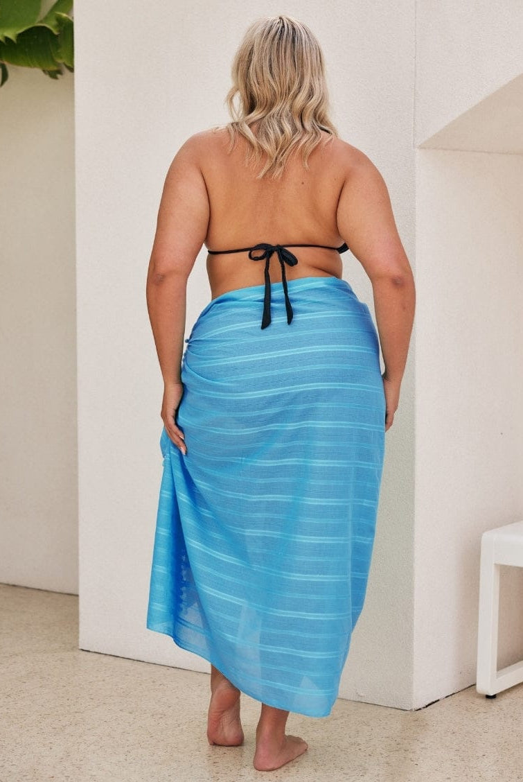 Woman wearing a blue striped sarong in an indoor setting