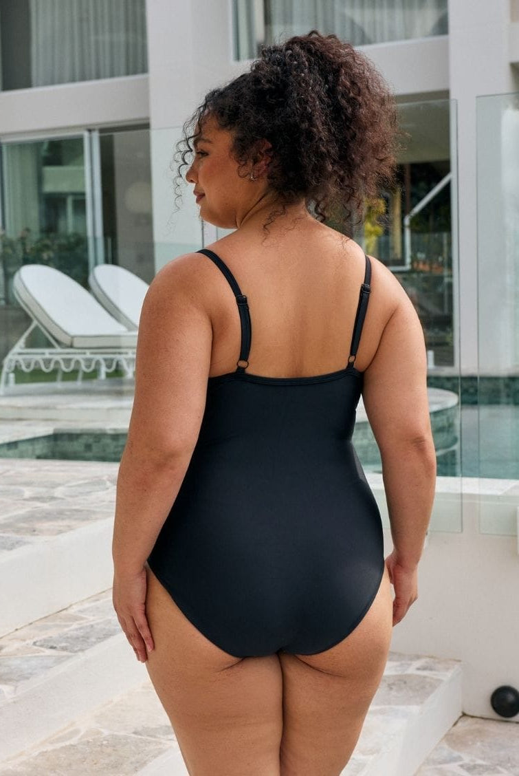 Back of model wearing a criss cross metallic black one piece with adjustable straps