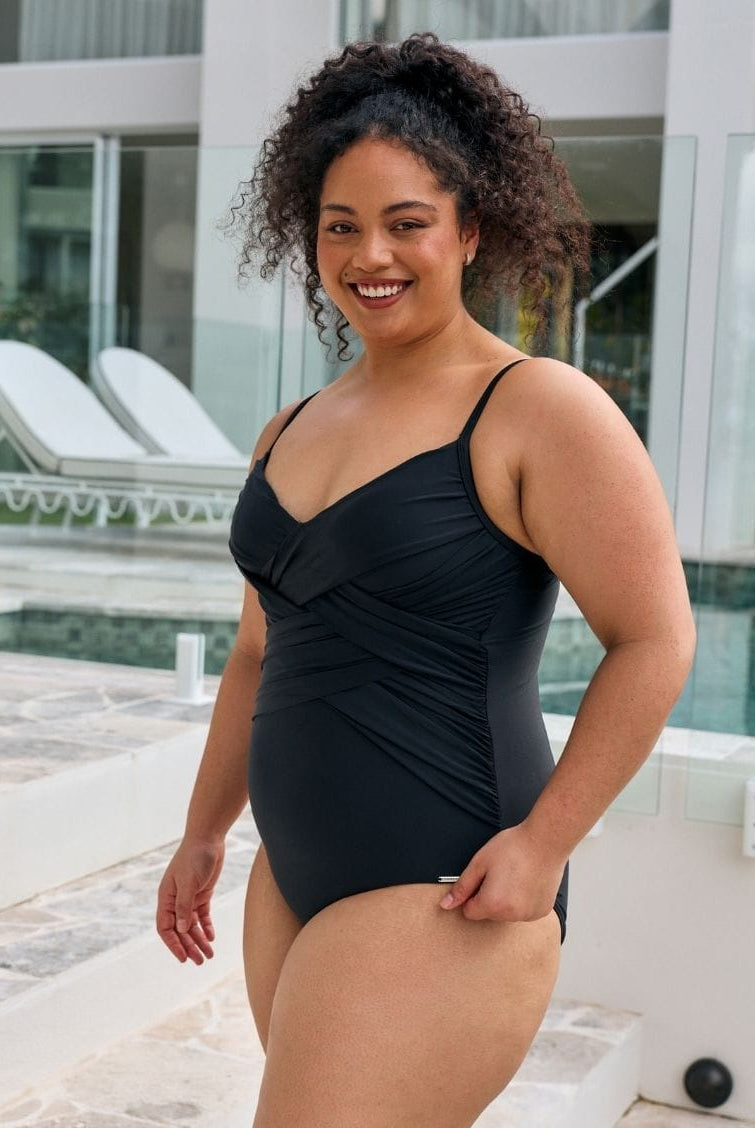 Brunette women wearing a criss cross one piece with shiny criss cross detail