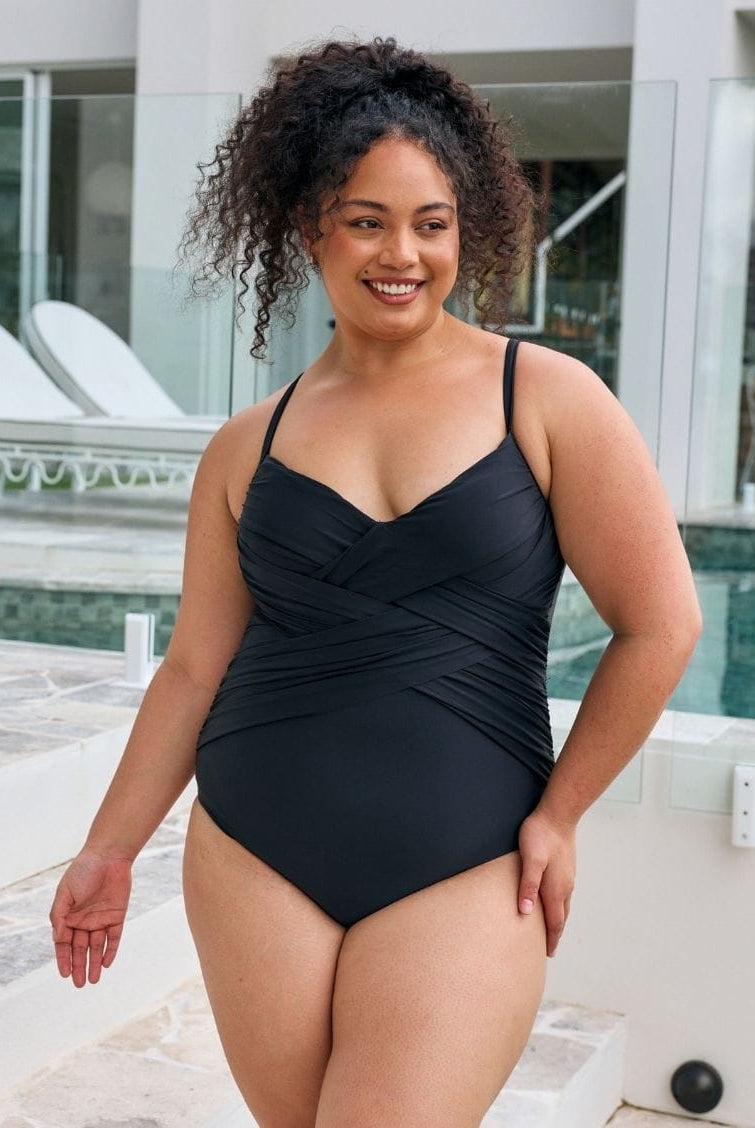 Brunette woman wearing a metallic black one piece with criss cross detail