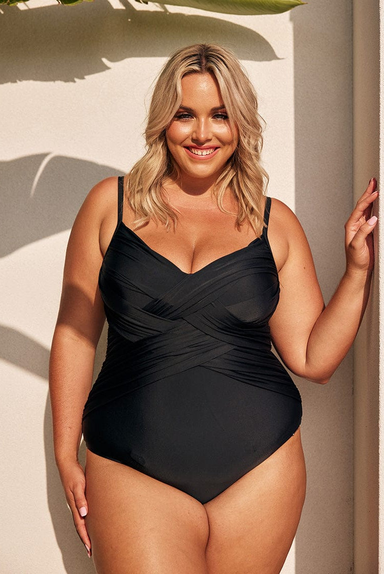 Blonde model wearing black criss cross one piece swimsuit
