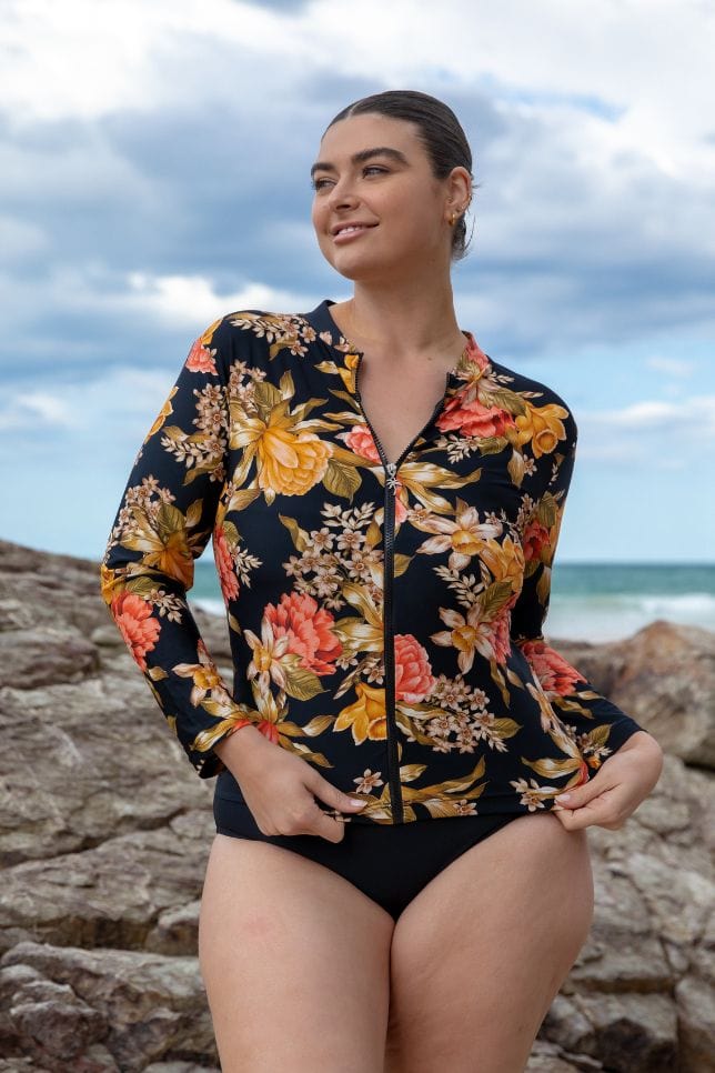 Model at beach wearing a long sleeve black floral sun top