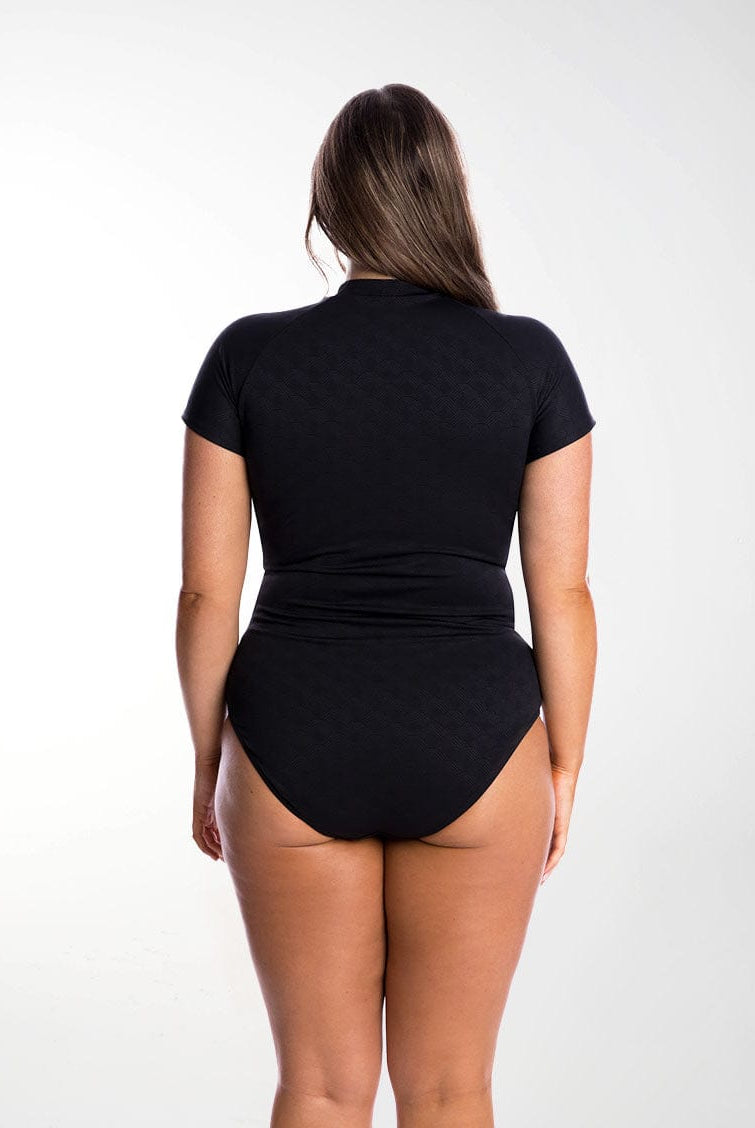 Model shows back of full coverage one piece swimsuit
