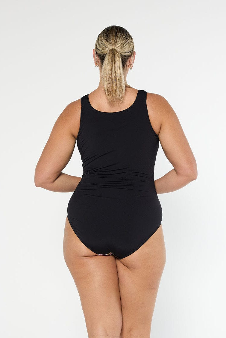 Blonde model wears black floral chlorine resistant sleeveless one piece with full coverage bottom and high back