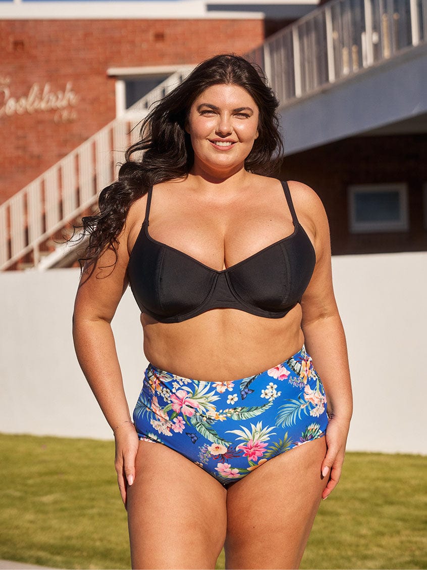Brunette model wears blue floral tummy control swim pant in high waisted style