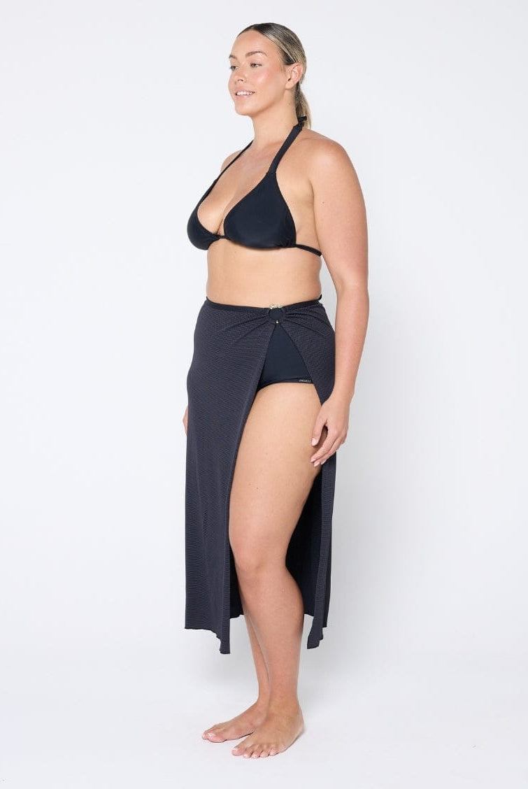 Woman wearing a black bikini and matching sarong on a white background