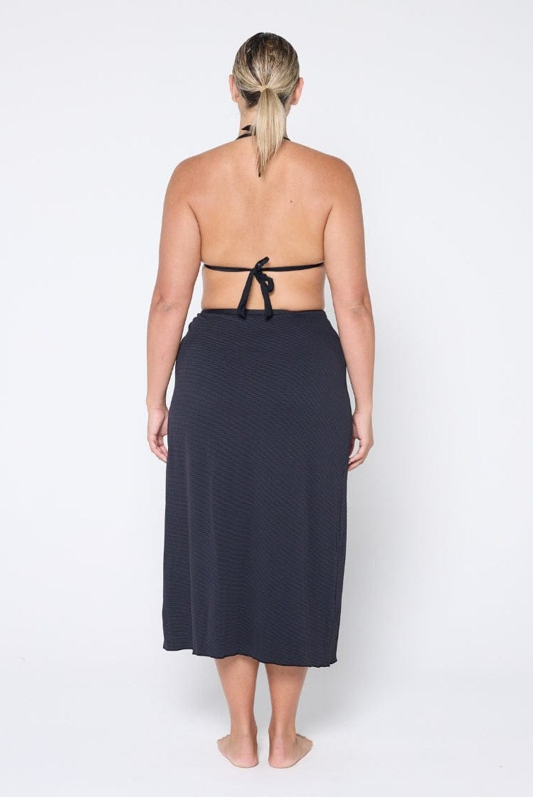 Woman wearing a black halter top and matching skirt on a white background