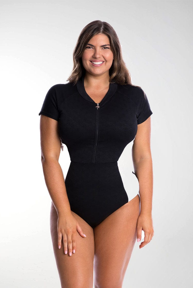 Brunette model wears flattering one piece swimsuit with zip front