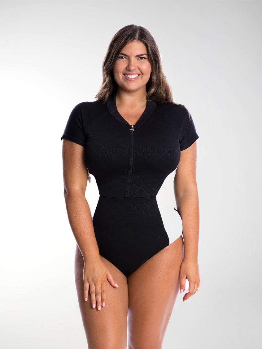 Brunette model wears flattering one piece swimsuit with zip front