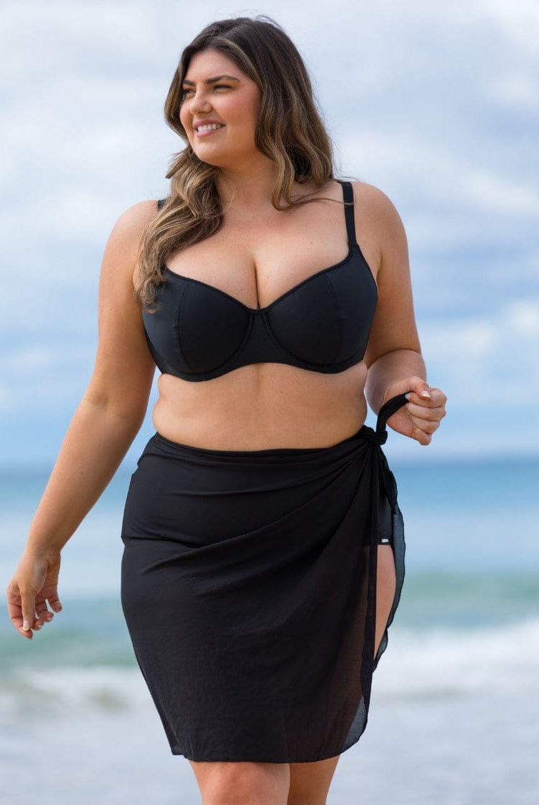 Woman wearing a black bikini and sarong on a beach