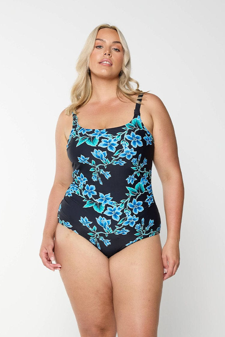 Blonde model shows blue floral swimsuit with scoop neckline and adjustable straps