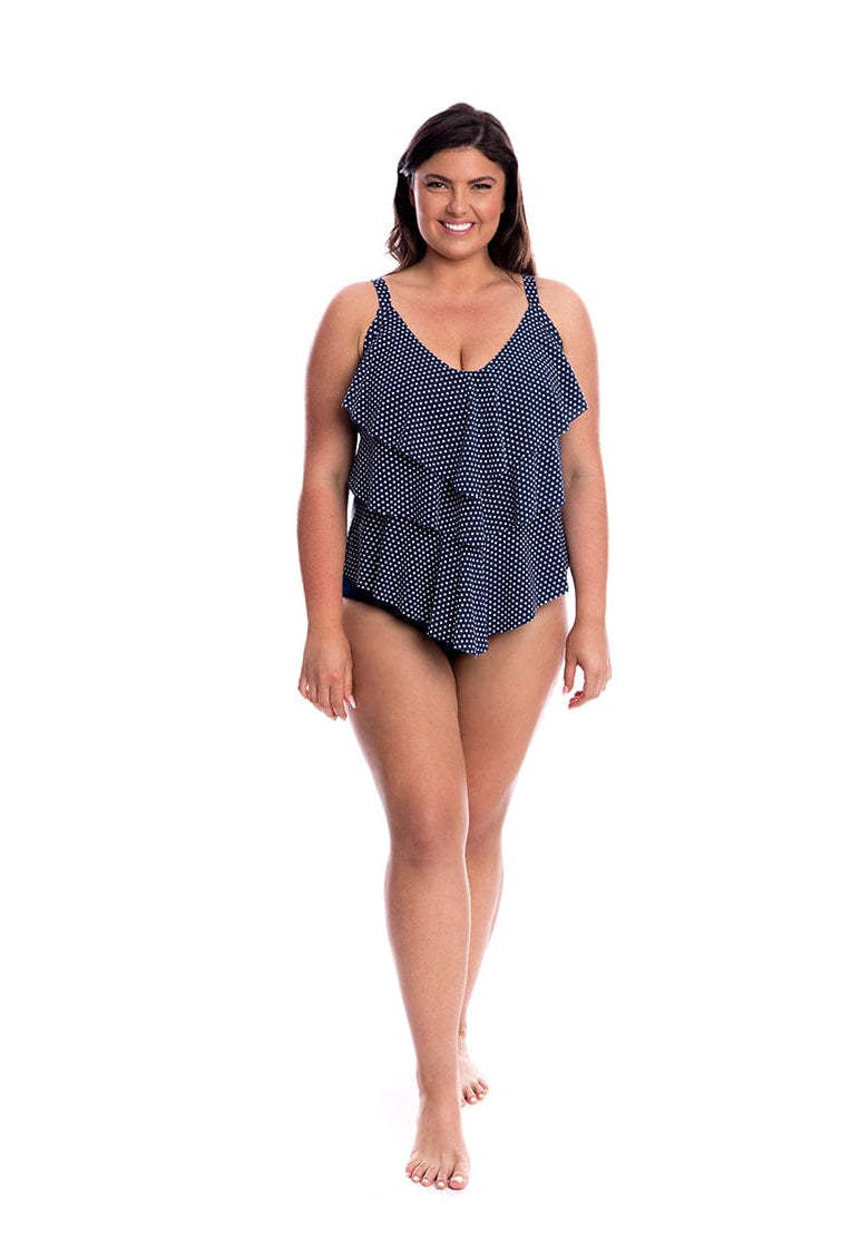 Woman wearing a navy blue polka dot swimsuit on a white background