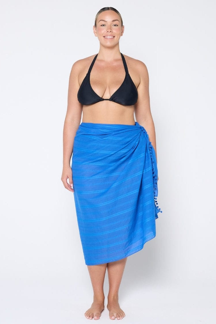 Woman wearing a black bikini and blue sarong on a white background