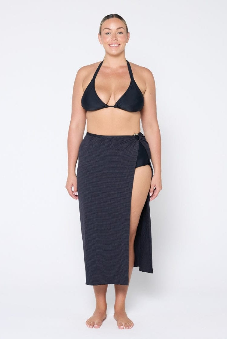 Woman wearing a black bikini and matching sarong on a white background