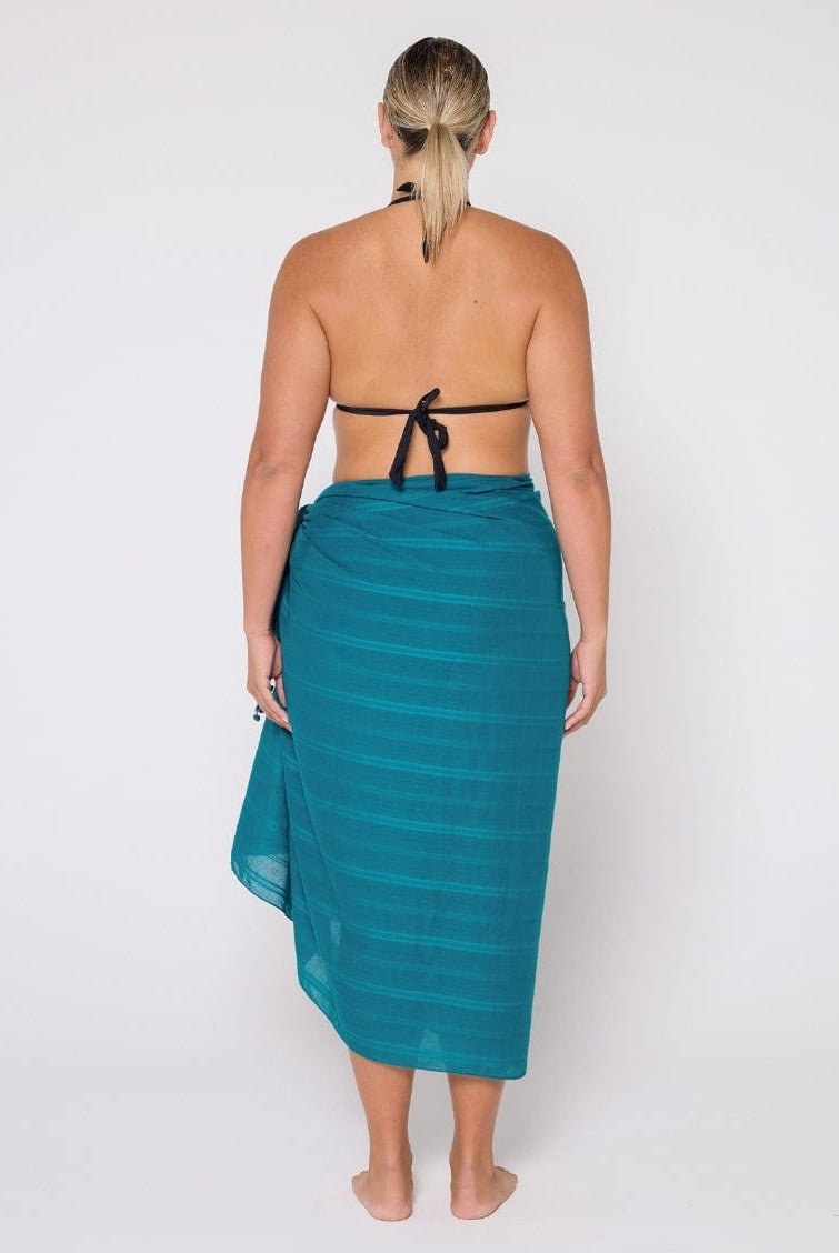 Woman wearing a teal sarong on a white background