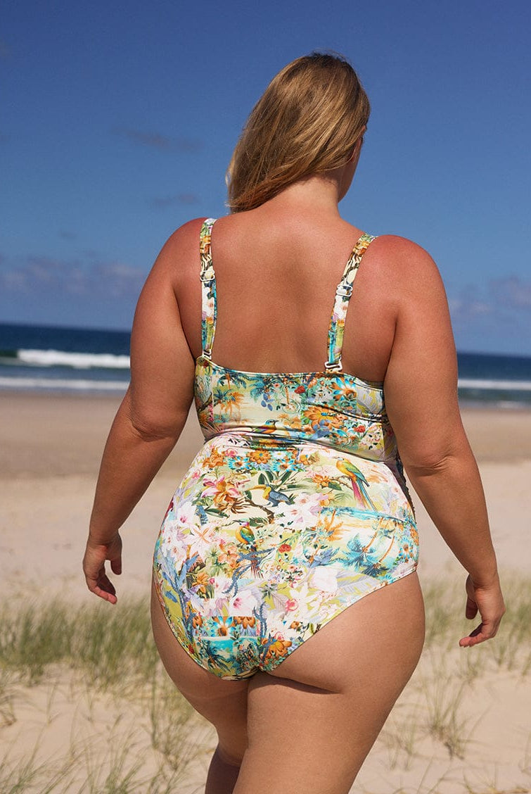 Woman wearing a floral swimsuit on a beach with ocean view