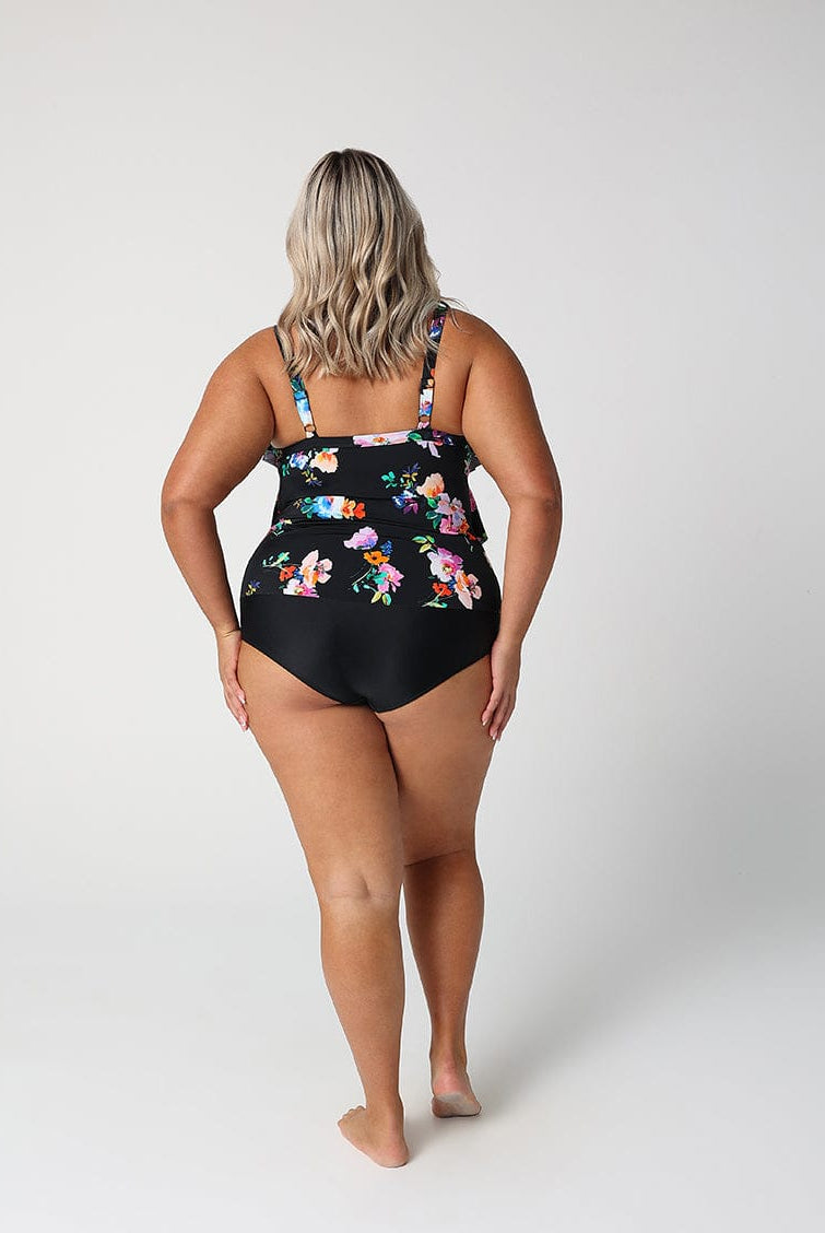 Woman wearing a black floral one-piece swimsuit on a white background