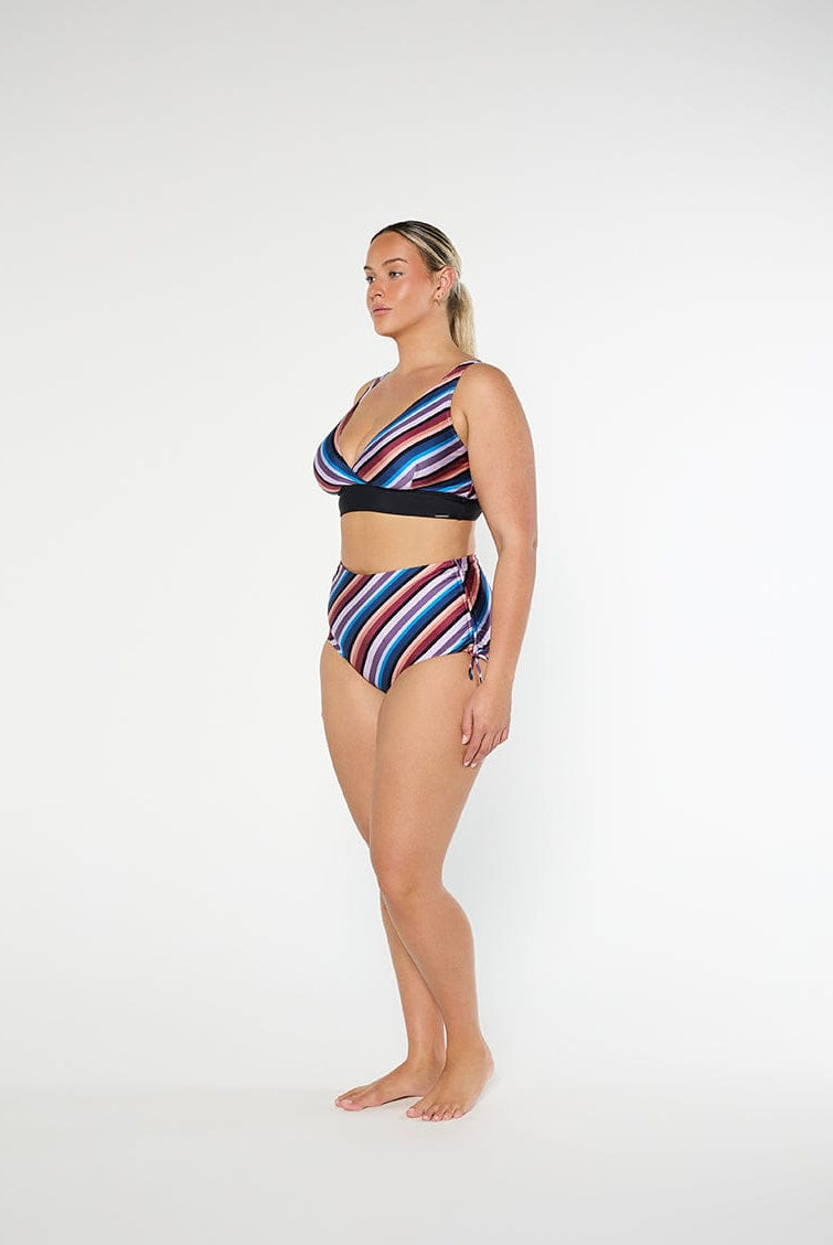 Woman wearing a colorful striped bikini set on a white background