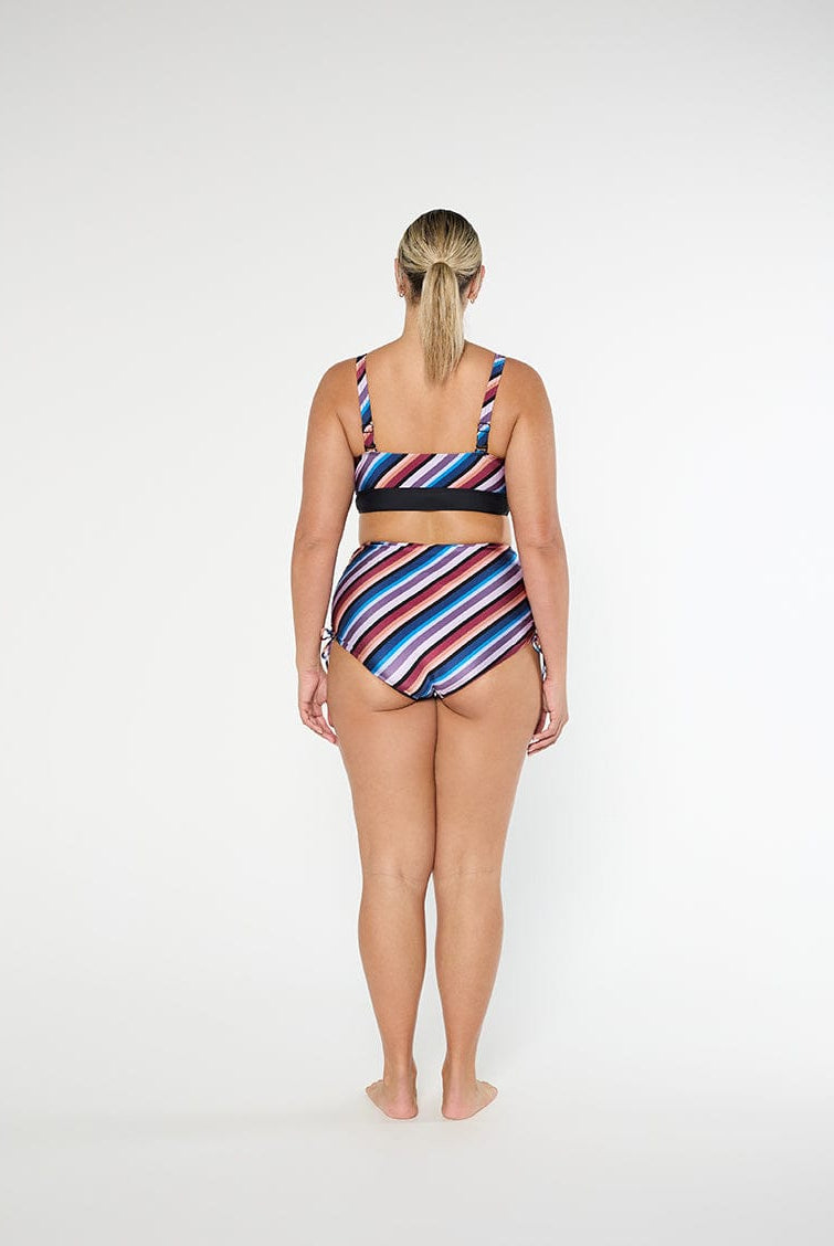 Woman wearing a colorful striped swimsuit on a white background