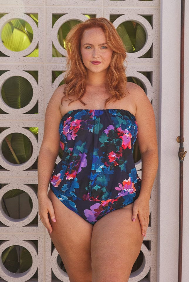 Red hair model wears navy floral flouncy bandeau one piece swimsuit