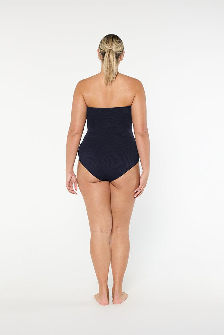Woman wearing a black strapless swimsuit on a white background