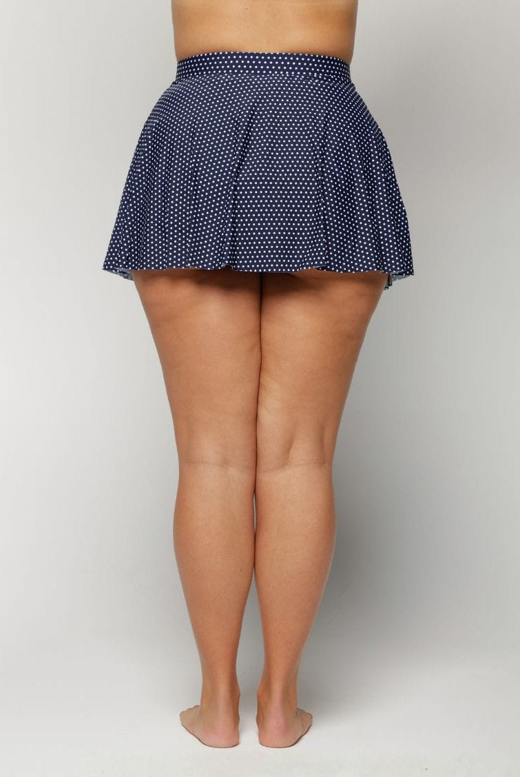 Navy polka dot skirt worn by a woman on a white background