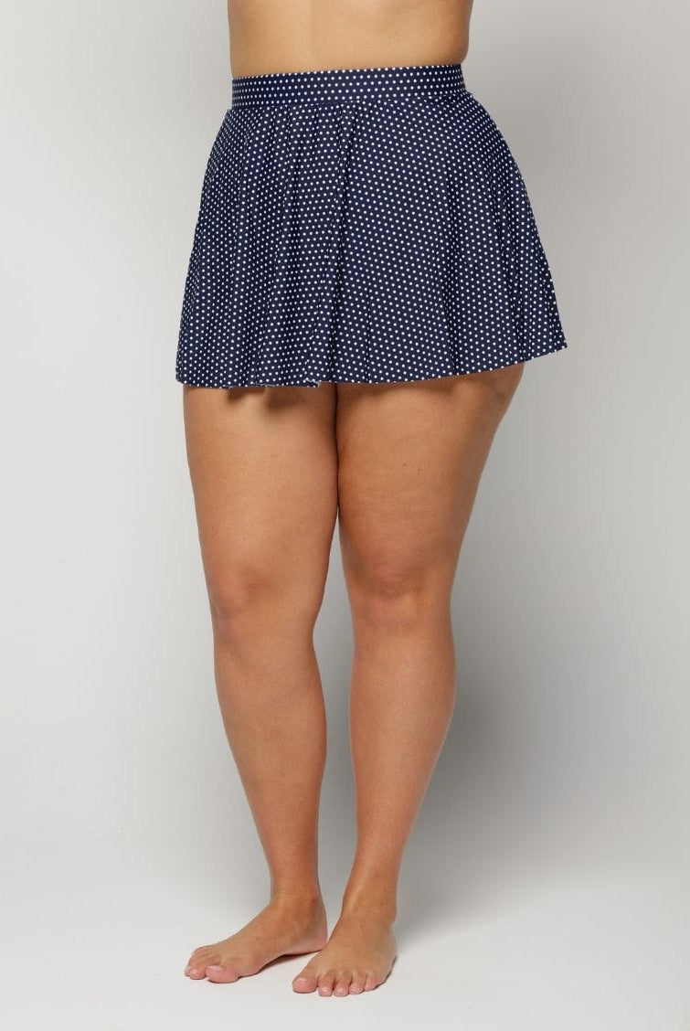 Navy polka dot skirt worn by a woman on a plain background
