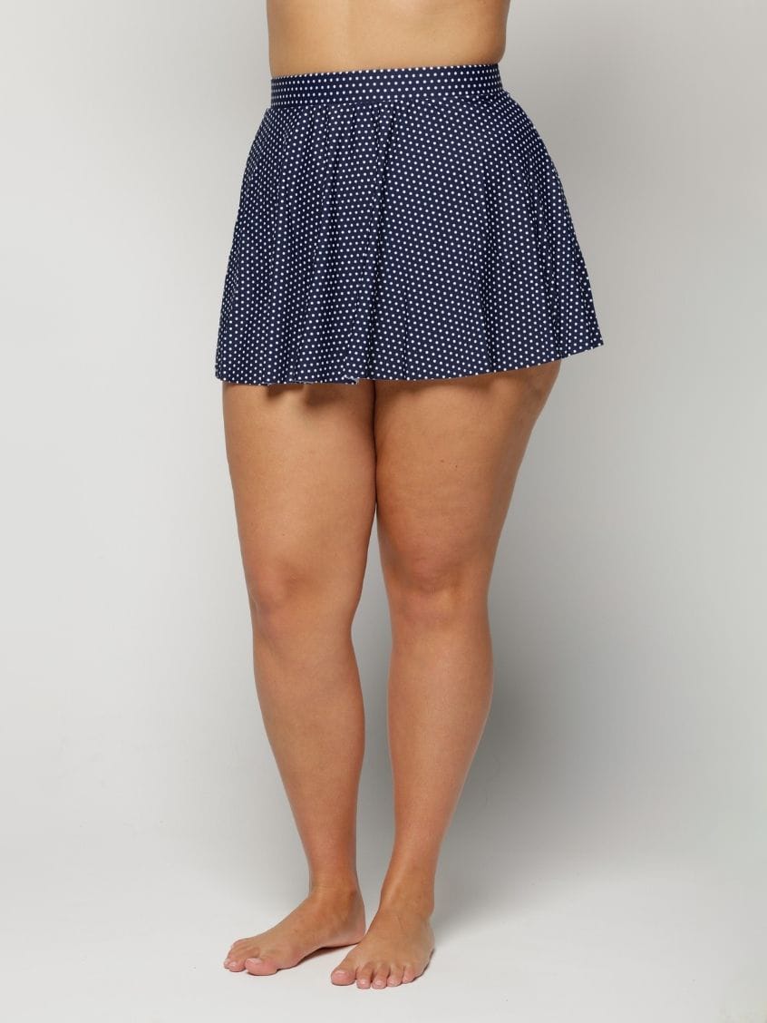Navy polka dot skirt worn by a woman on a plain background