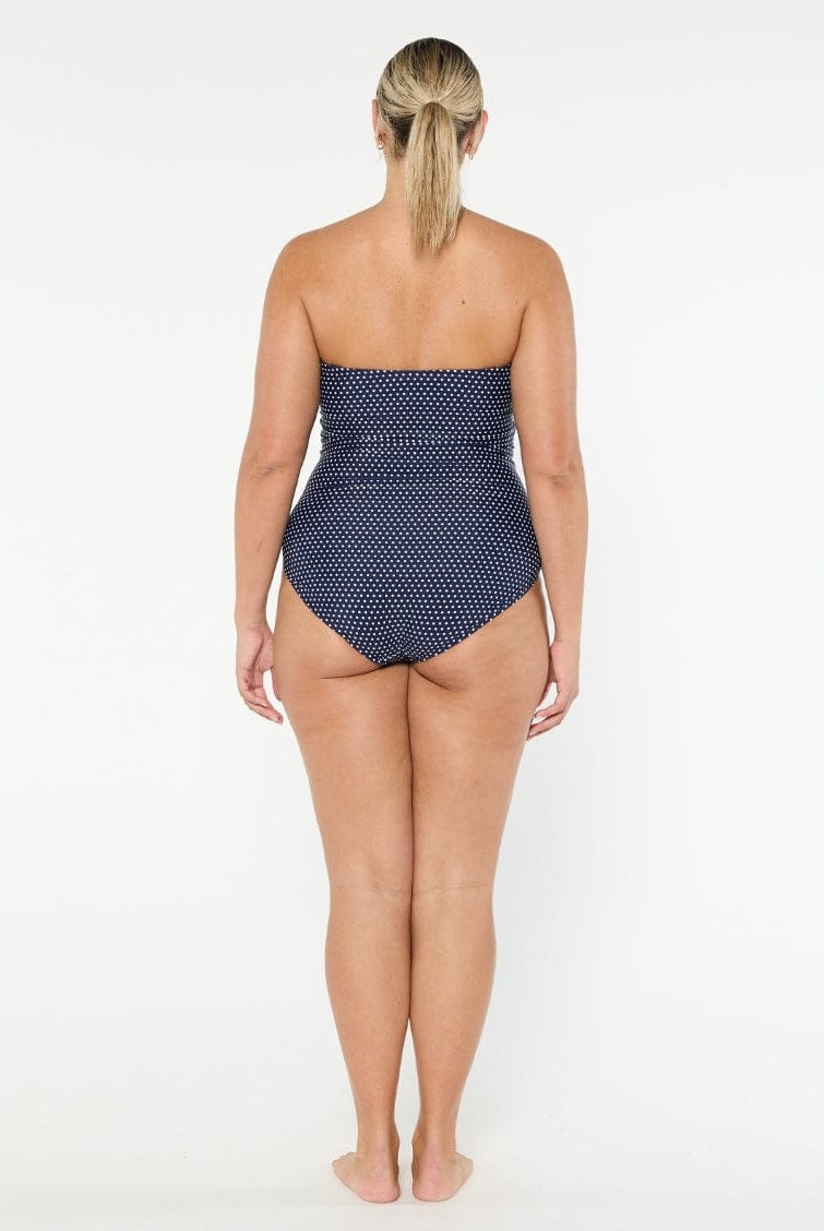 Woman wearing a strapless polka dot swimsuit on a white background