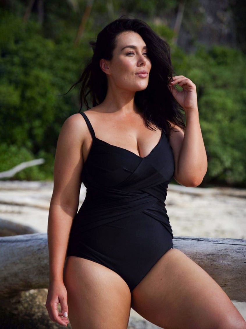 Model wearing black slimming criss cross one piece bathing suit