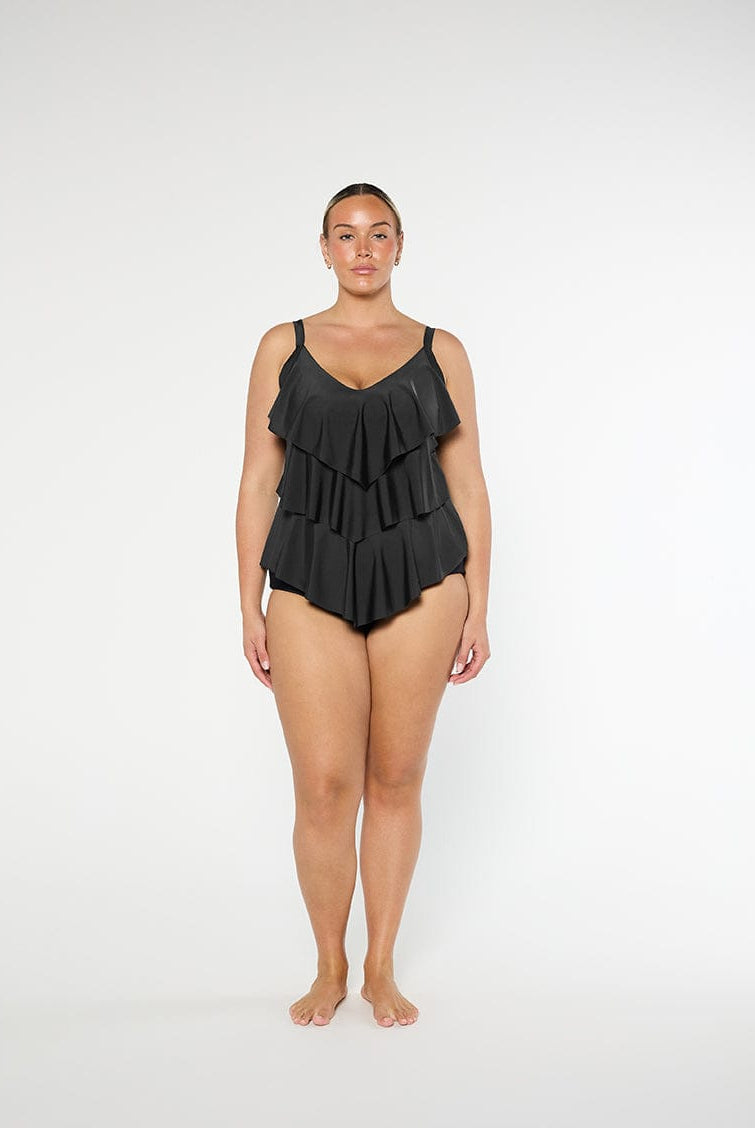 Woman wearing a black ruffled swimsuit on a white background