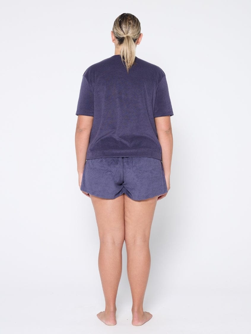 Person wearing a navy t-shirt and shorts set on a white background