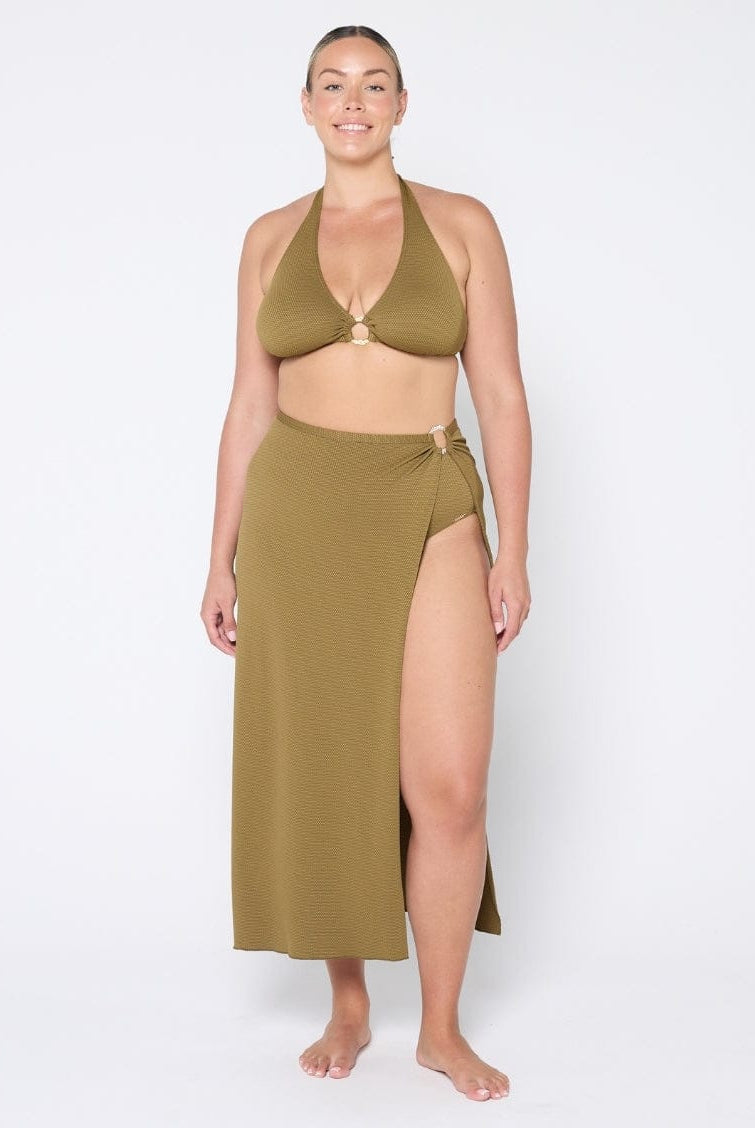 Woman wearing a green bikini set with a long skirt on a white background