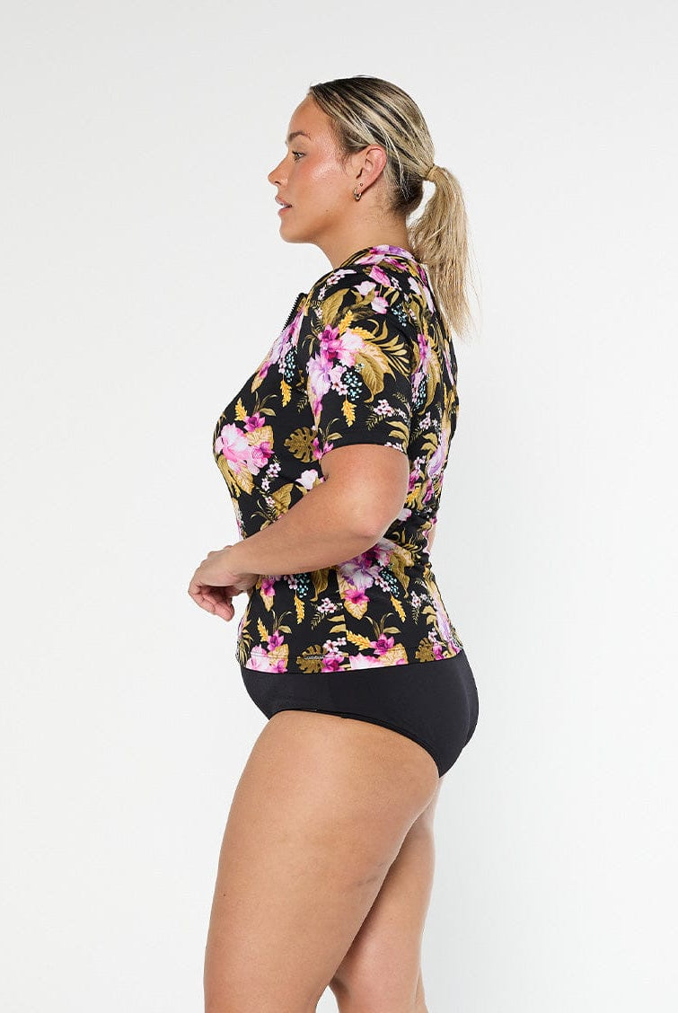 Blonde model shows the side of chlorine resistant short sleeve tropical print rash vest