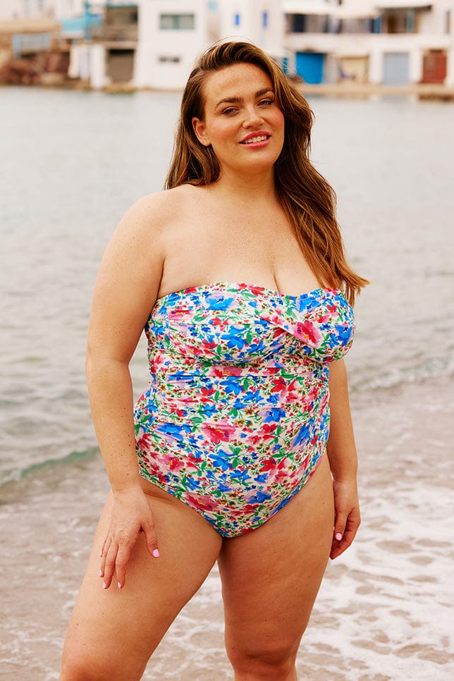 Brunette model wearing bright floral strapless one piece