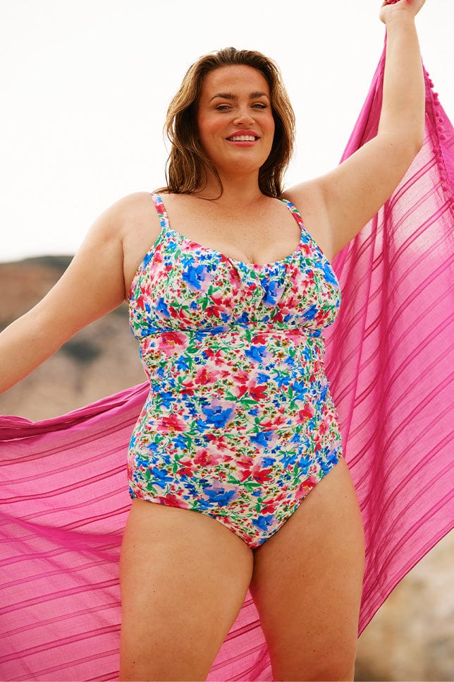 Brunette model wears bright floral underwire one piece swimsuit
