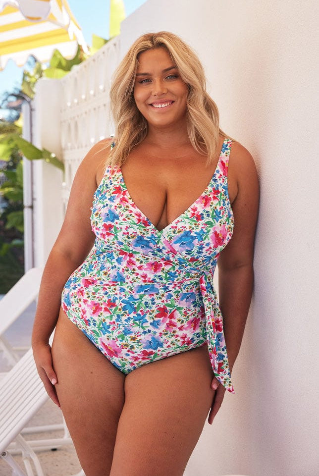 Blonde model wears bright floral waist tie one piece swimsuit
