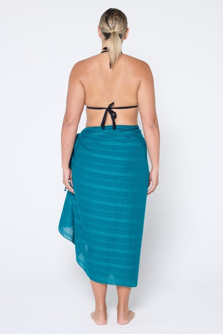 Woman wearing a teal sarong on a white background
