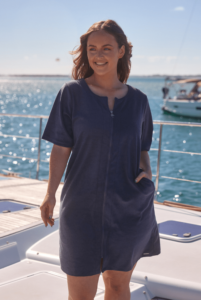Model wearing navy zip up beach dress on boat