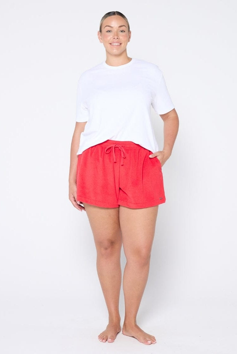 Person wearing red shorts and a white top on a white background