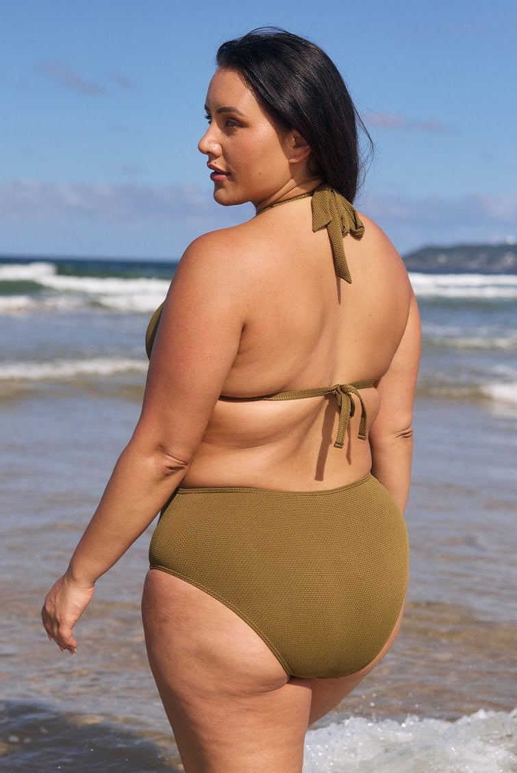 Brunette model wears tie neck bikini top in olive textured fabric
