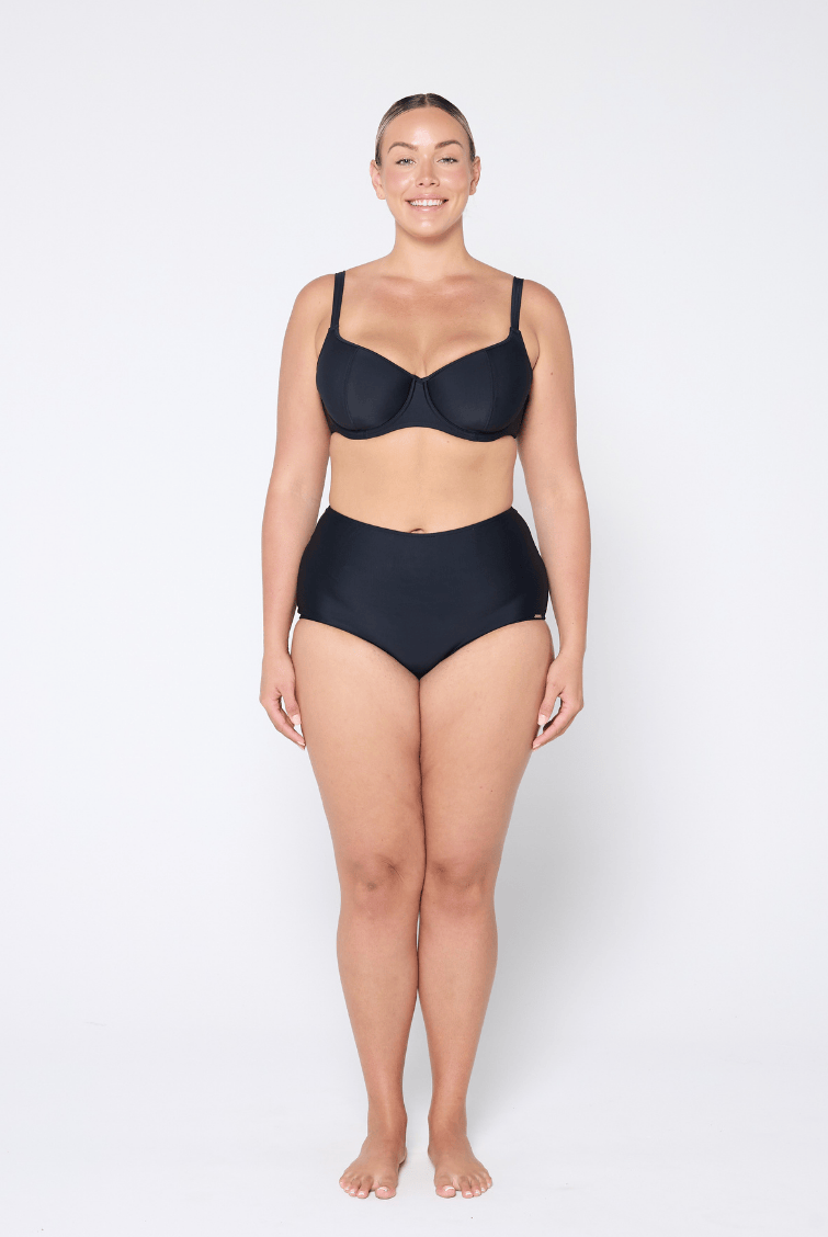 Woman wearing a black bra and high-waisted underwear on a white