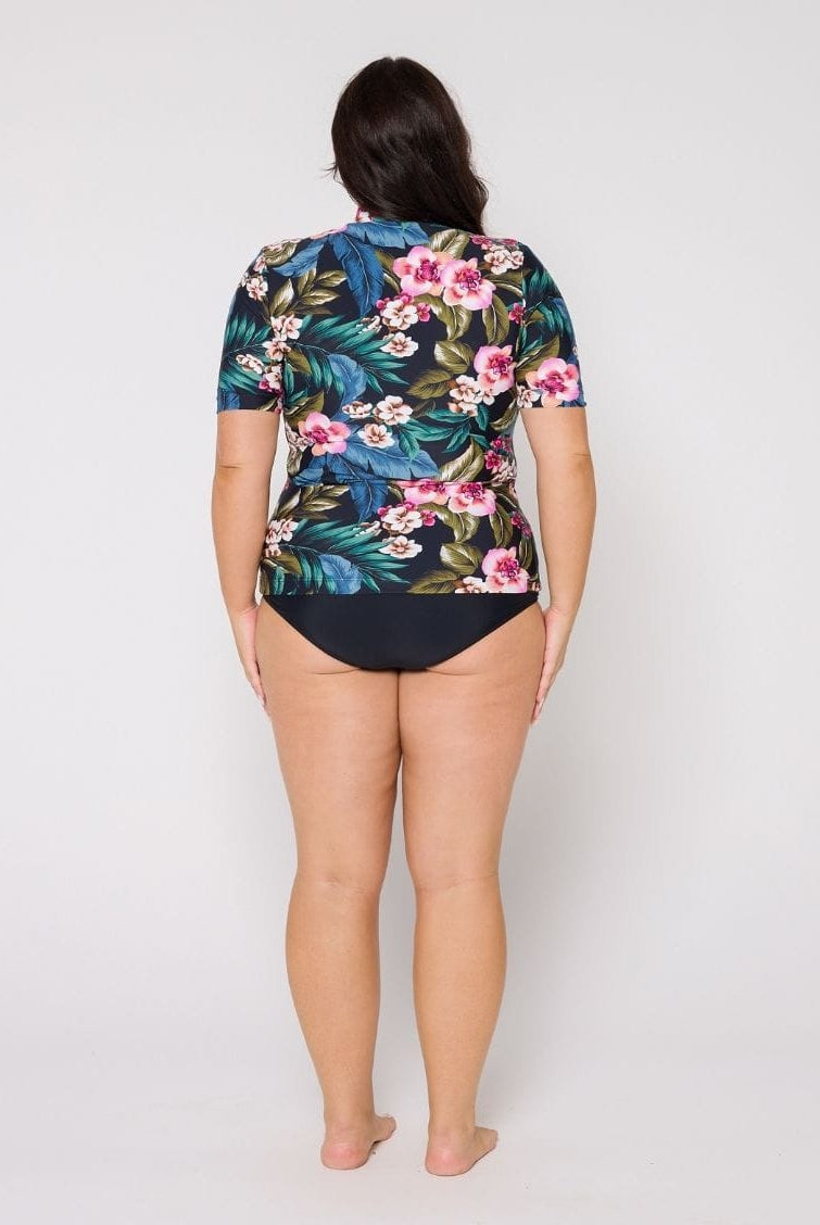 Model in studio wearing a floral short sleeve rash vest with zip front detail